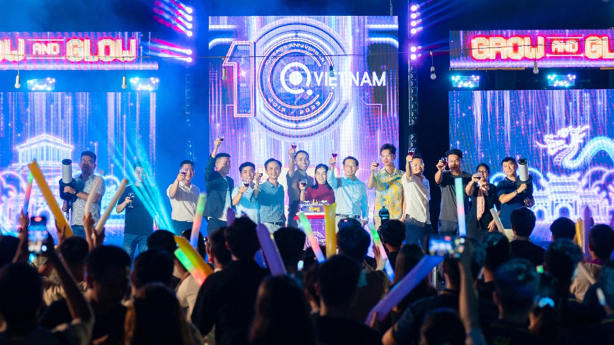 A large audience is visible in the foreground, holding up glow sticks