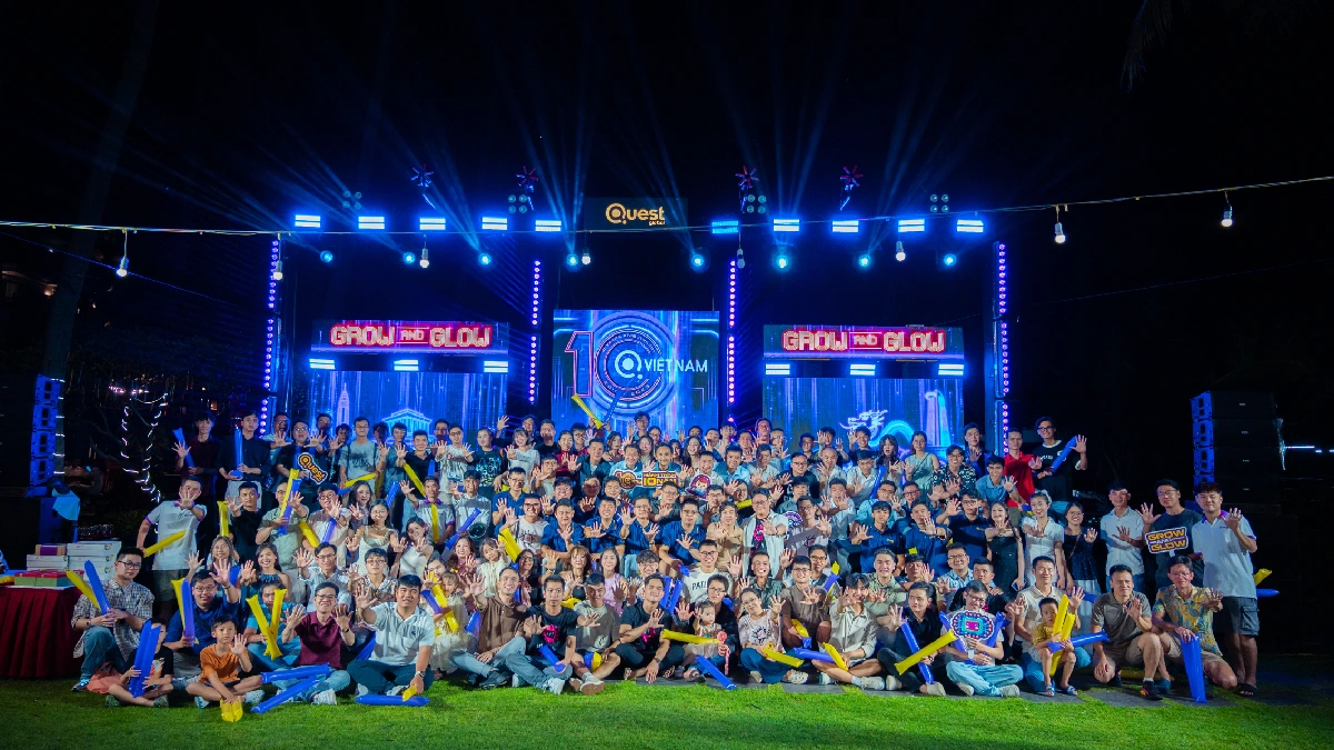 Large group posing in front of an illuminated stage at a night event