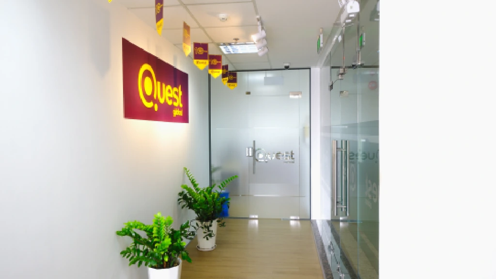 Modern office hallway featuring the brightly lit Quest Global logo sign